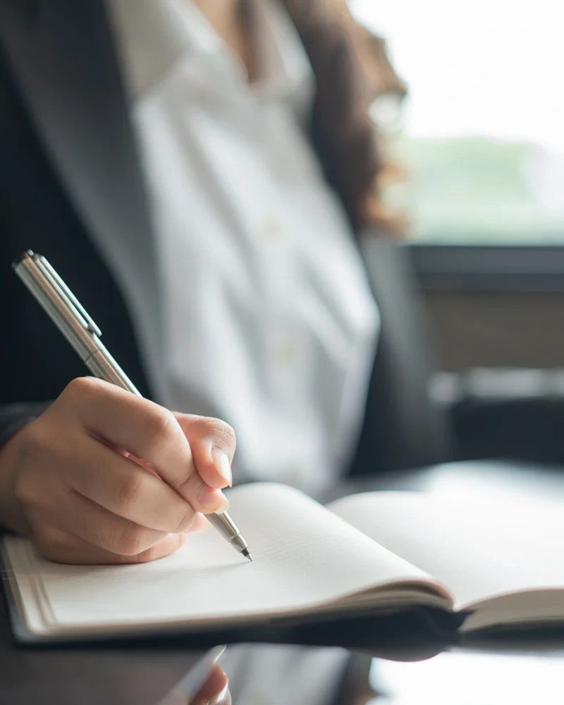 Chica empresaria escribiendo con bolígrafo en una libreta